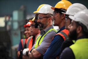 Several people wearing hard hats and safety glasses standing in a line
